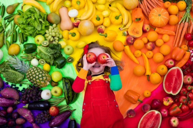 Child With Apple Over Eyes and Fresh Food Background